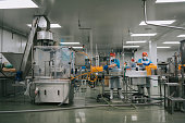 Asian Chinese juice factory workers sealing bottle cap of orange juice in production line