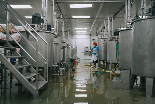 Factory worker cleaning flooring Factory interior storage tank section Filtering Machine and Tanks after production completed