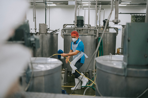 Factory worker cleaning flooring Factory interior storage tank section Filtering Machine and Tanks after production completed