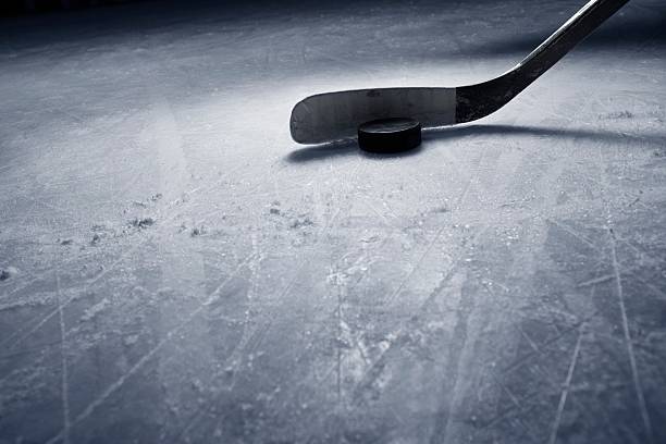 Hockey Stick and Puck on Ice A dramatic photograph of a hockey stick and puck on textured hockey ice. There is plenty of copy space.Click on an hockey puck photos stock pictures, royalty-free photos & images