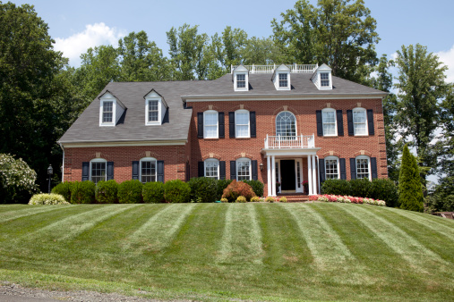 Large new American House in red brick with lovely green lawn in summer