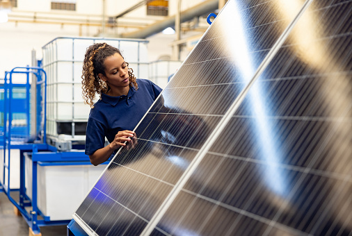 African American female engineer supervising the installation of solar panels at a factory
