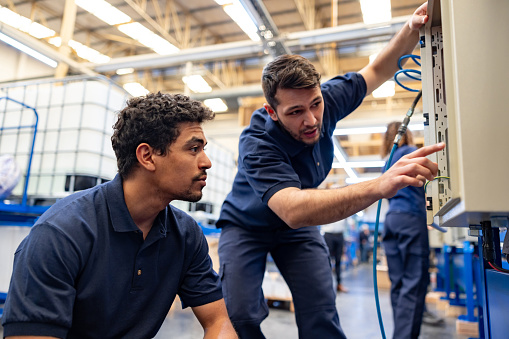 Team of Latin American engineers operating machines at a manufacturing factory