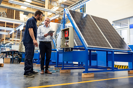 Latin American foreman supervising the operation of solar panels with the operator at a factory