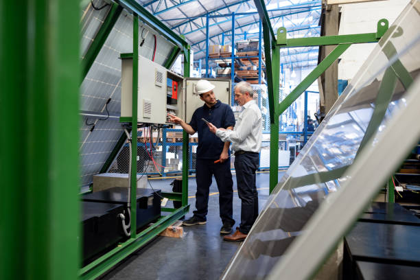 istock Foreperson supervising an engineer fixing a solar fuse box at a factory 1828385353
