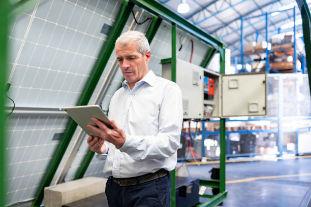 Engineer controlling the operation of a solar panel from a tablet at a factory
