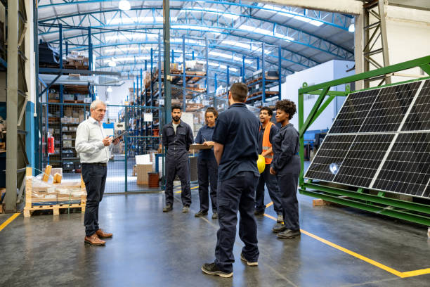 Manager talking to a group of employees at a solar panel factory