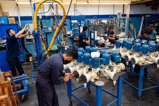 Group of Latin American employees working at a water pump factory - manufacturing concepts