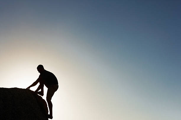 istock Silhouette image of a man climbing rock 182838896