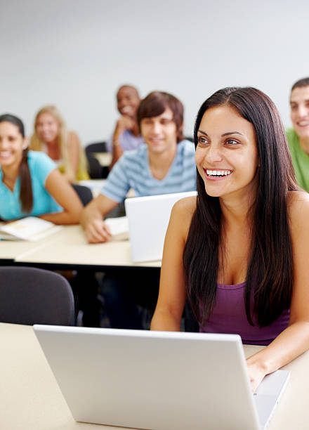 istock Smiling lady using laptop with friends in the background 182840384