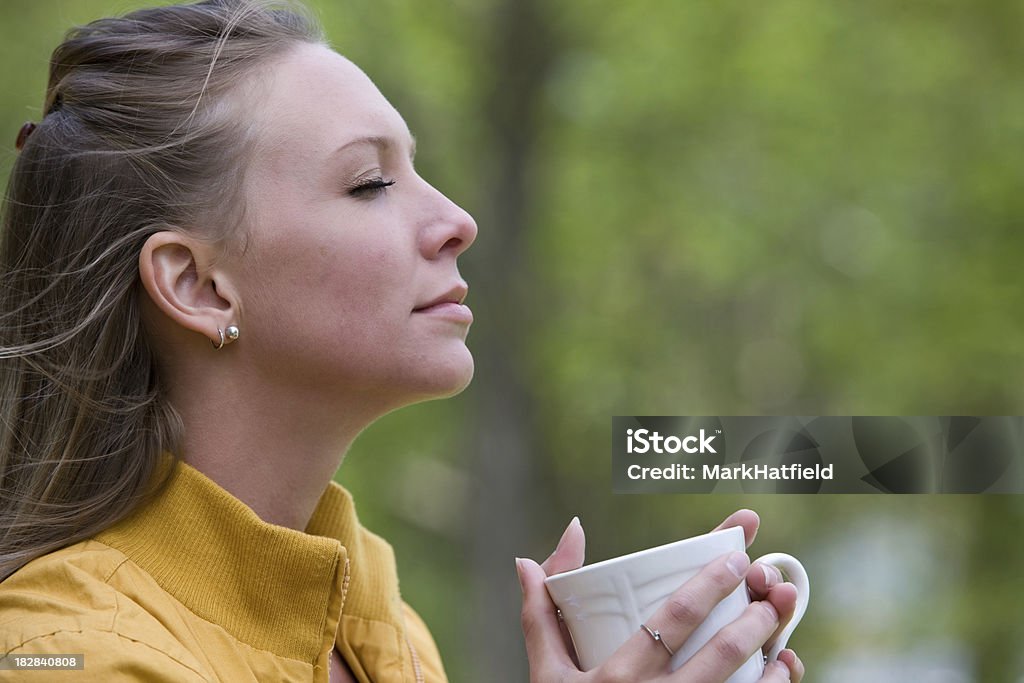 Woman Meditates With Cup Of Coffee Woman Meditates With Cup Of Coffee.  Very shallow depth of field with green woods and trees in the background. 20-24 Years Stock Photo