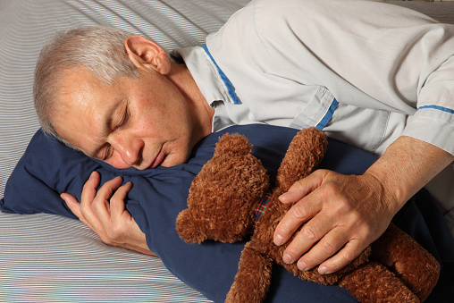 Grown man in deep sleep in bed with Teddy Bear