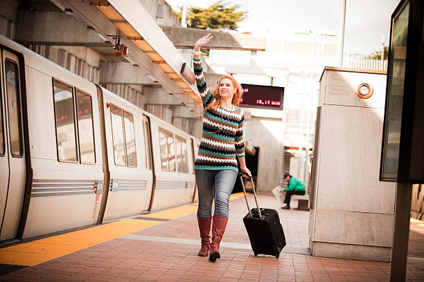 A girl with a suitcase runs futilely after a departing subway train.