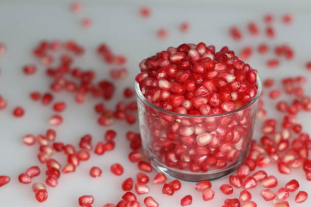 Vibrant pomegranate fruit and red pearl like arils glisten in a glass bowl, showcasing freshness and juicy allure Vibrant pomegranate fruit and red pearl like arils glisten in a glass bowl, showcasing freshness and juicy allure. Shot on white background. Pomegranate juice stock pictures, royalty-free photos & images