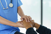 Close-up hand of female doctor holding hand of patient.