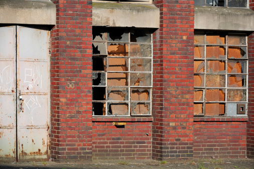 Abandoned industrial red brick building with broken windows. Urban decay. Urban blight. Poor economy. Economic meltdown. Factory closing. Job loss.