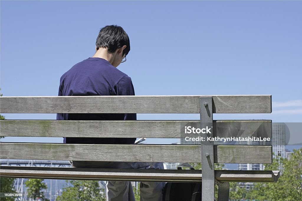 Canadaian masculino Teen fica sozinho em um banco de parque, Vancouver - Foto de stock de Adolescente royalty-free