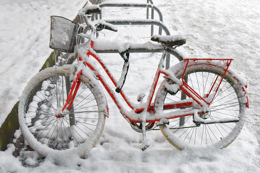Bicycle on the street covered with snow. Bicycle with basket parked.