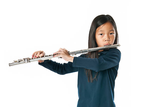 Little skillful girl playing flute with sheet of music
