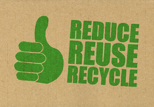 Reduce reuse recycle stamped on to the side of recycled cardboard in green ink. Thumbs up hand drawn and created by myself.