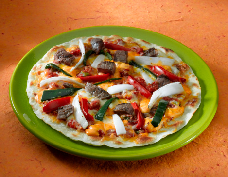 A steak and veggie pizza Mexican style on a crispy tortilla.