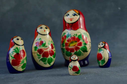 Russian matroshka dolls with selective focus on the youngest son. mamushkass family on uniform gray background