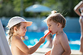 Siblings at swimming pool in summer licking ice cream
