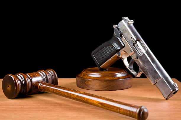 деревянный молоток судьи и ручное оружие в таблице для преступности наказания концепции - gun laws стоковые фото и изображения