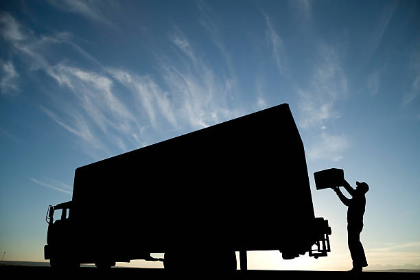 Loading Up A silhouette of a courier putting a package a delivery truck. silhouette of a stop stock pictures, royalty-free photos & images