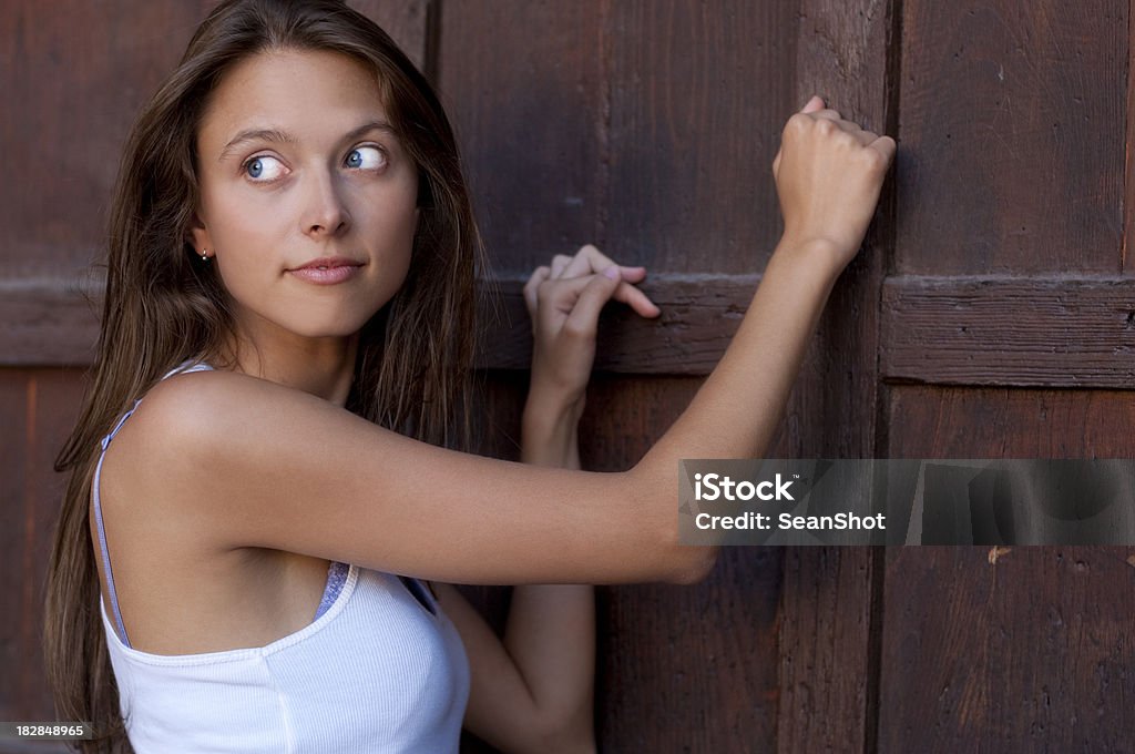 Girl Knocking Wooden Door Beautiful girl knocking on old dark wooden door Door Stock Photo