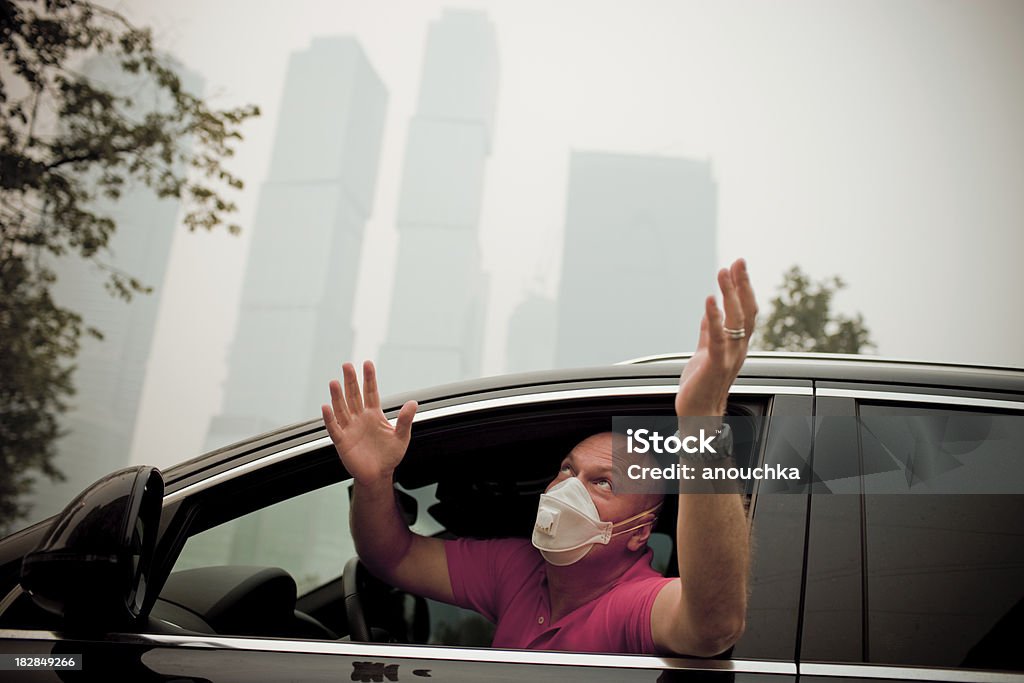 Mature Man sitting in his car and praying for rain "Mature Man sitting in his car and praying for rain, Moscow in smoke from forests fires..." Car Stock Photo