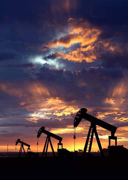 Oil Wells at Dawn, Vertical "Vertical image of oil wells during Wyoming sunrise. New dawn of petroleum energy resources. Dark blue border at top, bottom,  and corners for text." oil well stock pictures, royalty-free photos & images