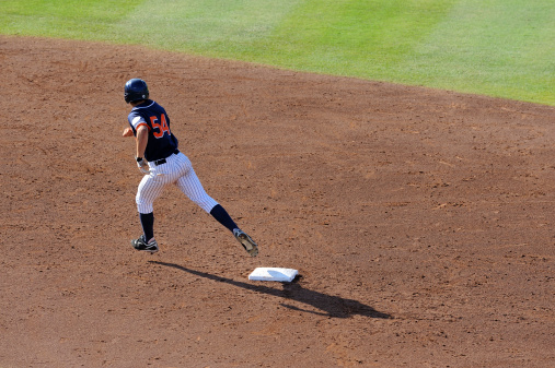 A baseball player rounds second base during a game.