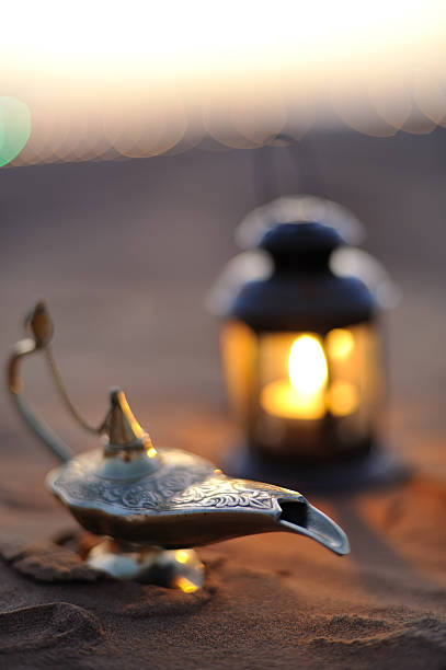 arabic dubai an arabic oil lamp lying in the desert with traditional lantern during sunset. very shallow focal length.  concept image of arabic theme. image taken in dubai outskirt magic lamp photos stock pictures, royalty-free photos & images