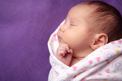 Sleeping, swaddled newborn baby girl