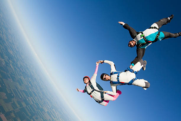 foto stock sin royalties: tres skydivers in freefall - female with group of males fotos fotografías e imágenes de stock