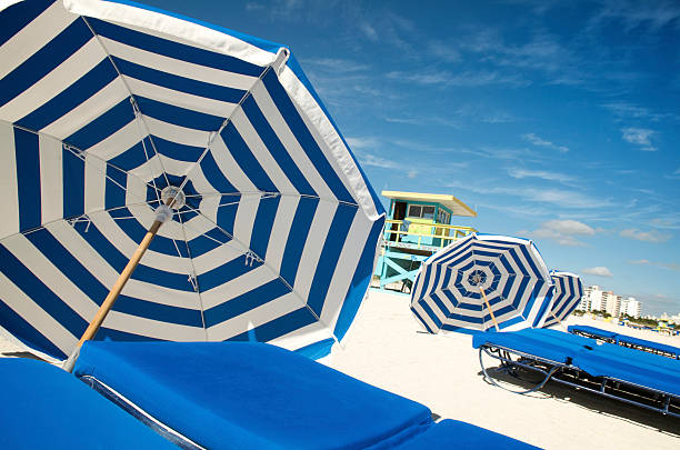 Bright summer scene of crisp blue and white striped beach umbrellas next to loungers