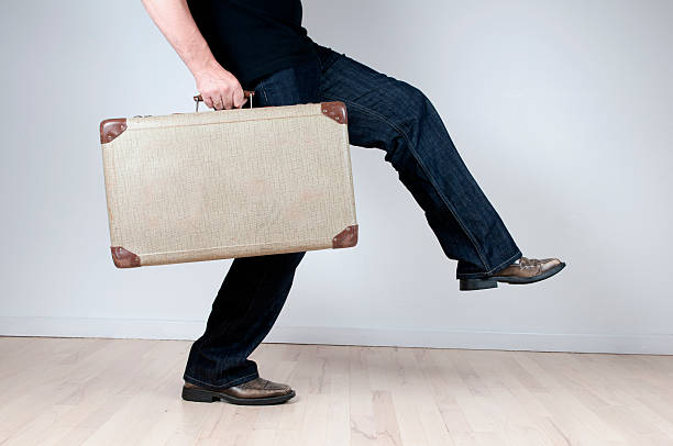 istock Man takes a big step forward holding a retro suitcase 182851498