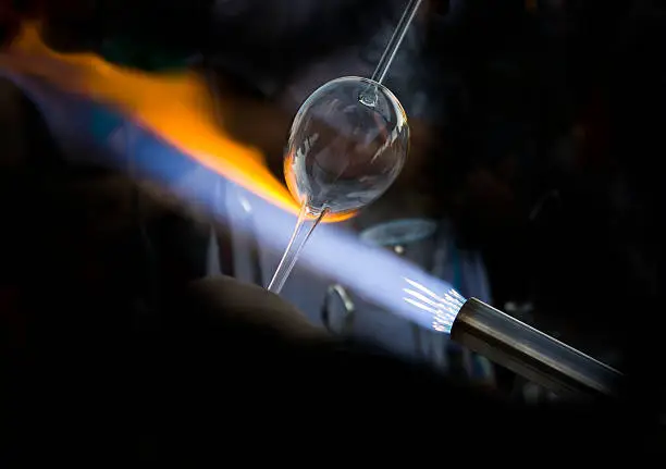 Glass blower making a glass. Background has been darkened for more dramatic effect.