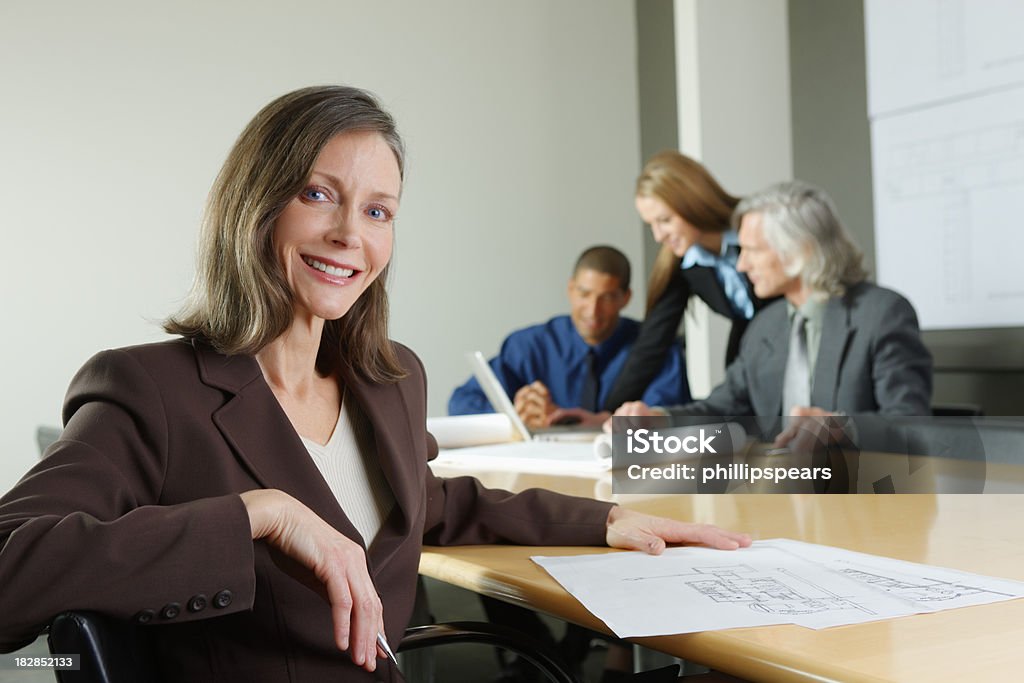 Executivo feminino sorrindo com colegas no fundo - Foto de stock de 30 Anos royalty-free