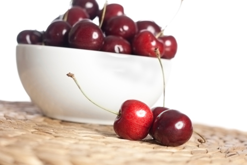 A bowl of cherries with a small group sitting next to the bowl