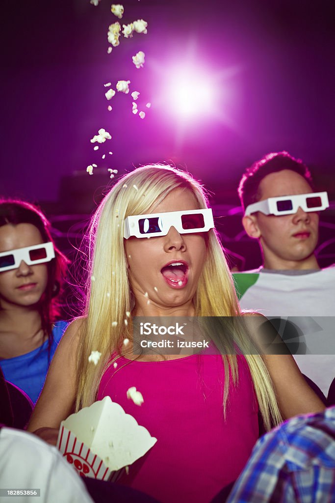 Young people in 3D move theater "Young adult people wearing 3D glasses, sitting in the cinema  and watching scary 3D move. Young woman wearing in pink shouting." 3-D Glasses Stock Photo