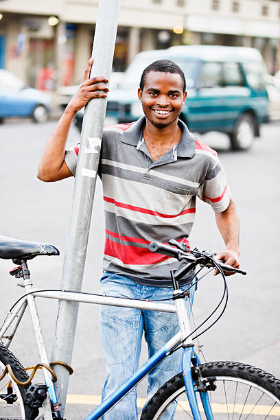 sorridente jovem homem africano com bicicleta na rua - africa african descent south bicycle imagens e fotografias de stock