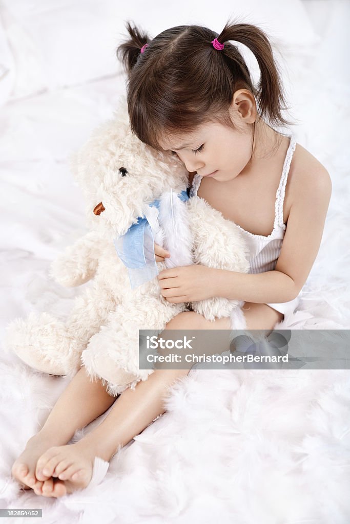 Triste niña abrazándose Osito de peluche en la cama - Foto de stock de Edredón libre de derechos