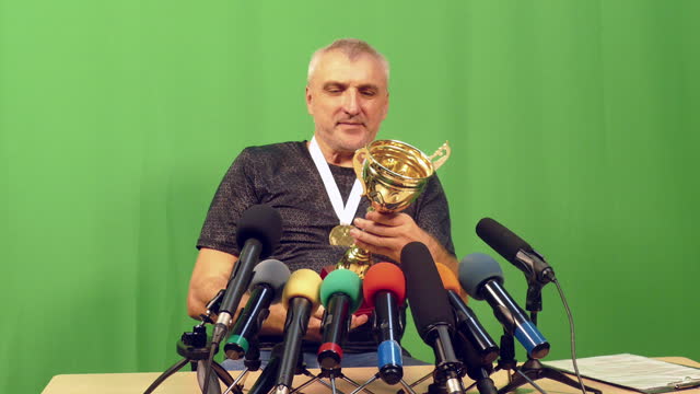 sports champion - medalist at a press conference in front of press microphones