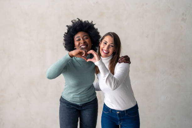 istock Studio shot of a two diverse young women forming a heart shape 1828549949