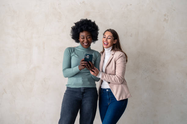 istock Two multicultural female friends scrolling through social media on a smart phone in a studio 1828551534
