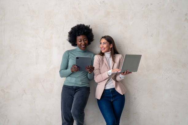 istock Two multiethnic businesswomen using digital tablet and laptop. Studio shot 1828554709