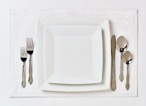 Empty plate and fork and knife with napkin on white background. Table setting. Top view, flat lay.