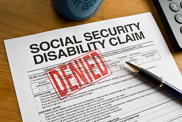 Social Security Claim Denied on a desk Denied rubber stamped on a social security disability claim. begging social issue photos stock pictures, royalty-free photos & images